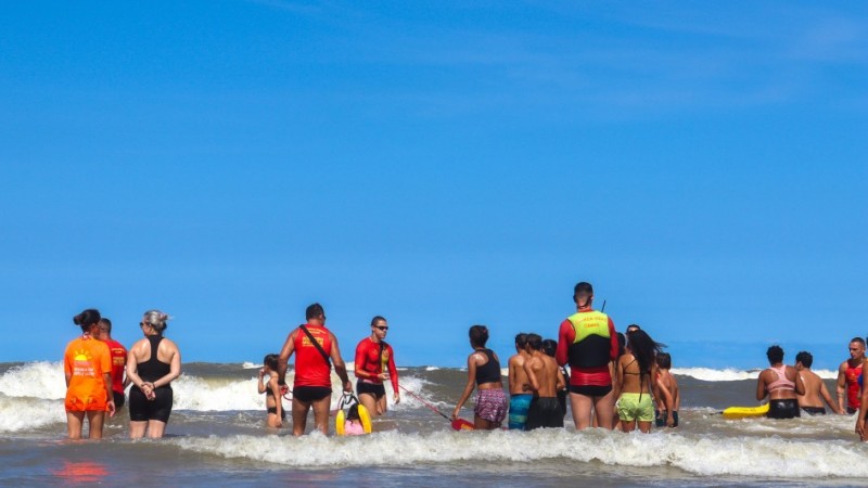 Crianças brincam no mar com supervisão de agentes do Corpo de Bombeiros militar