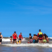 Crianças brincam no mar com supervisão de agentes do Corpo de Bombeiros militar